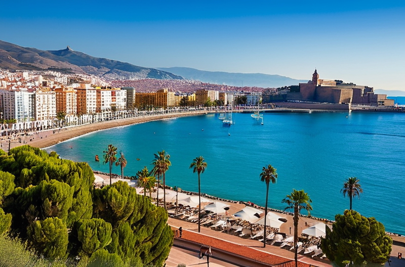 Panoramic view of Málaga harbor with boats, the Mediterranean sea, and the city's historic center with mountains in the background