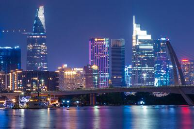 Ho Chi Minh City skyline at night with illuminated skyscrapers reflected on the Saigon River