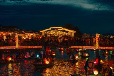 Hoi An ancient town at night with traditional yellow buildings and colorful lanterns reflected in the river